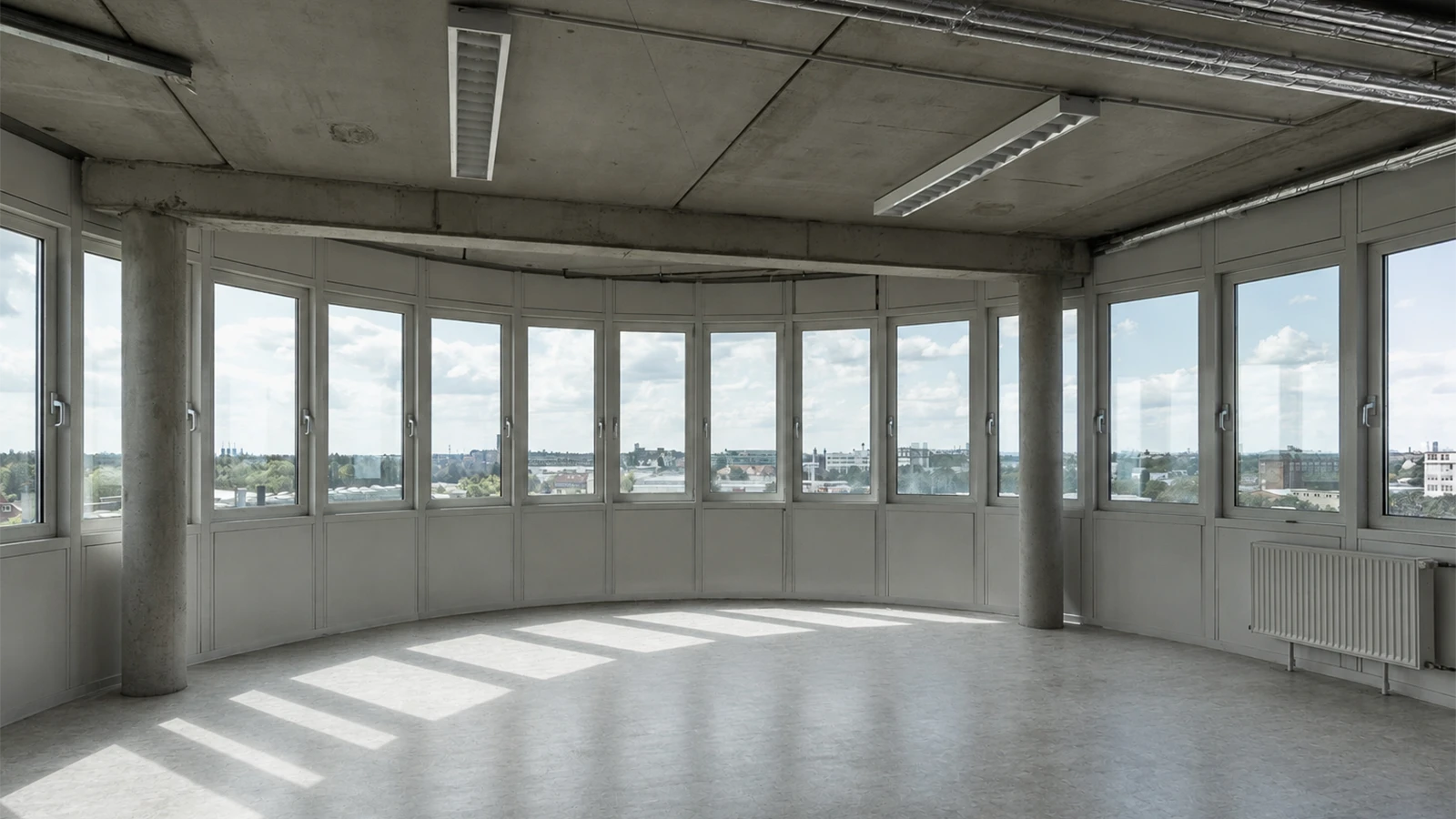 Großzügige Fläche im 6. Obergeschoss des GODU mit gebogener Fensterfront und Betonboden