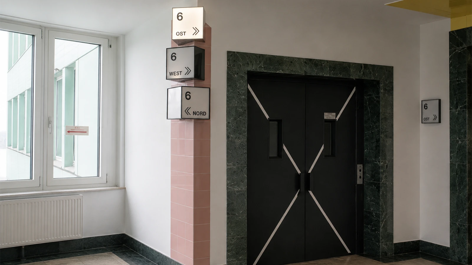 Lastenaufzug im 6. Obergeschoss des GODU mit Wegweisung zu Nord-, Ost- und Westflügel